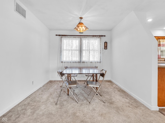 carpeted dining area with visible vents, baseboards, and an inviting chandelier