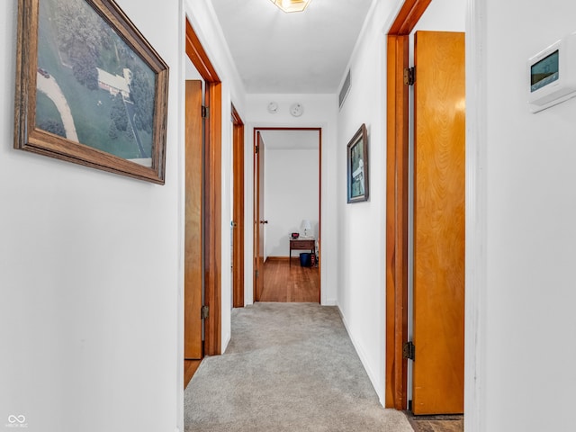 hallway featuring baseboards, visible vents, and carpet flooring