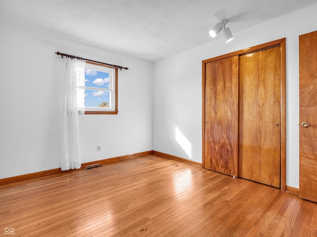 unfurnished bedroom with light wood-type flooring, visible vents, and baseboards