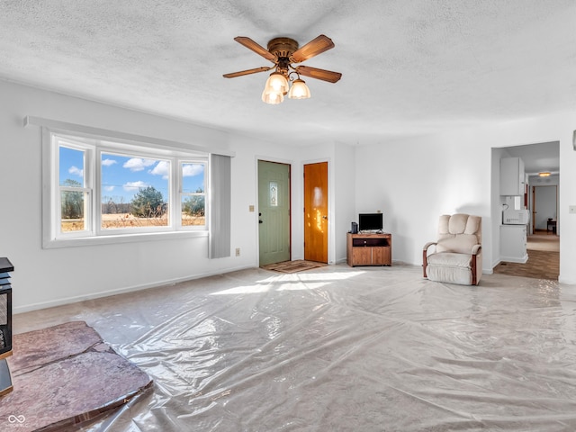 living area with ceiling fan, baseboards, and a textured ceiling