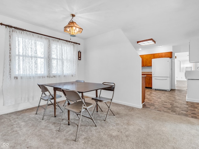 dining area with an inviting chandelier, baseboards, and light colored carpet