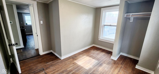 unfurnished bedroom featuring dark wood-type flooring, multiple windows, and baseboards