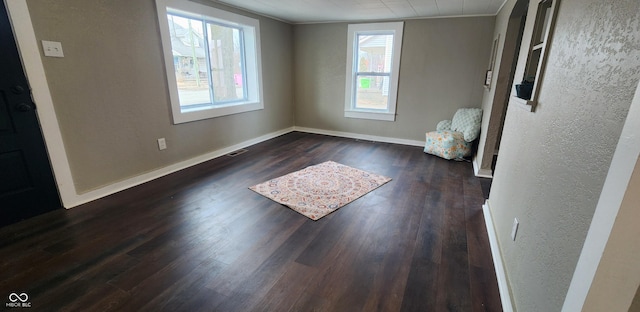 interior space featuring dark wood-style floors, visible vents, ornamental molding, and baseboards