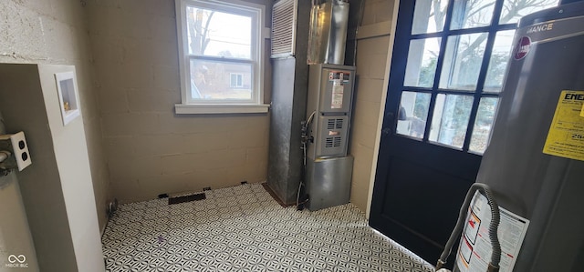 bathroom with concrete block wall, a wealth of natural light, gas water heater, and heating unit