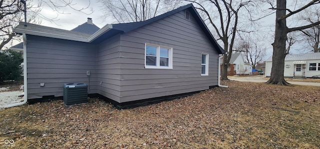 view of side of home featuring a chimney and cooling unit