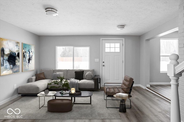 living area featuring light wood-style flooring, baseboards, and a textured ceiling