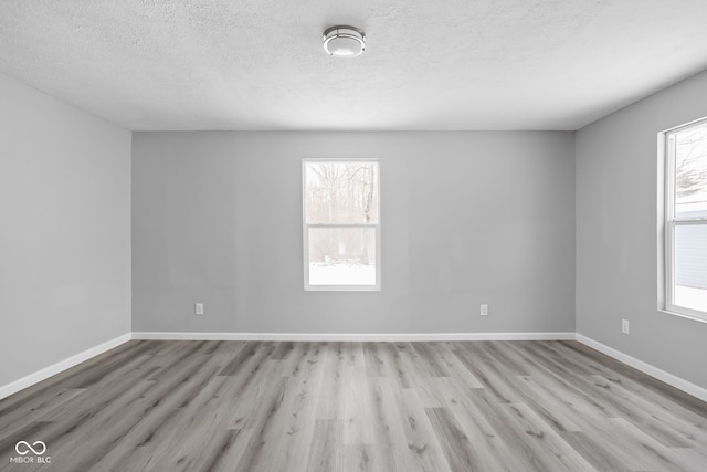 unfurnished room with light wood-type flooring, a wealth of natural light, and baseboards