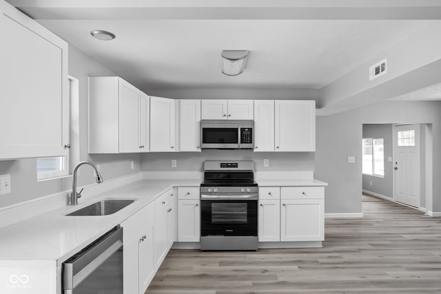 kitchen with visible vents, white cabinets, stainless steel appliances, light countertops, and a sink