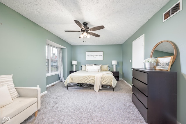 carpeted bedroom featuring baseboards, a textured ceiling, visible vents, and a ceiling fan