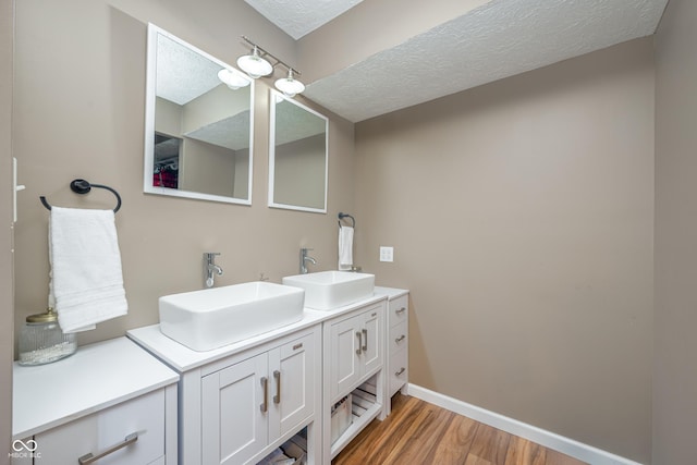 full bathroom featuring a sink, a textured ceiling, baseboards, and wood finished floors