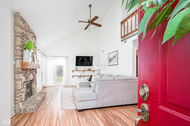 living area featuring high vaulted ceiling, a fireplace, wood finished floors, visible vents, and a ceiling fan