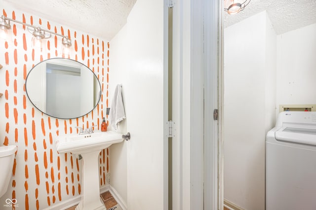 bathroom featuring washer / clothes dryer, baseboards, a textured ceiling, and toilet