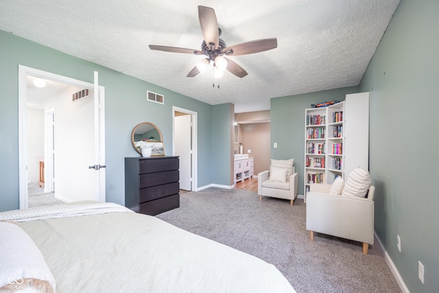 carpeted bedroom featuring baseboards, visible vents, and a textured ceiling