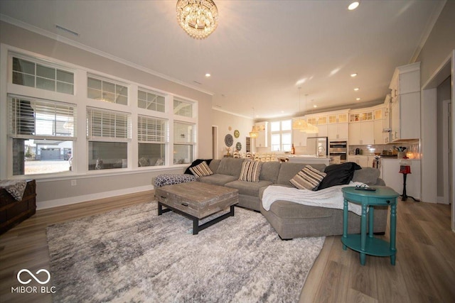 living area with baseboards, ornamental molding, and wood finished floors