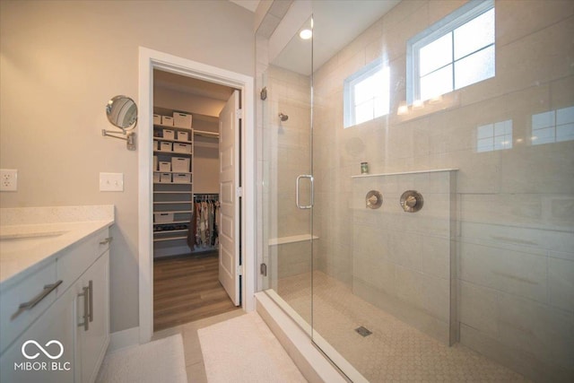 full bath with tiled shower, a walk in closet, and vanity