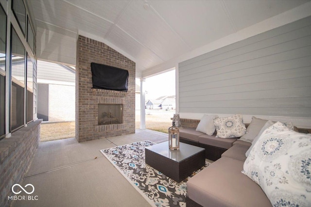 living area with an outdoor brick fireplace, lofted ceiling, and plenty of natural light