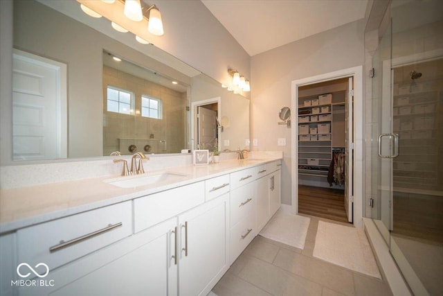 full bathroom featuring double vanity, a stall shower, and a sink