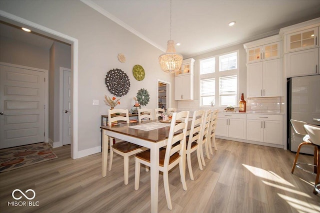 dining room with recessed lighting, crown molding, baseboards, light wood finished floors, and an inviting chandelier