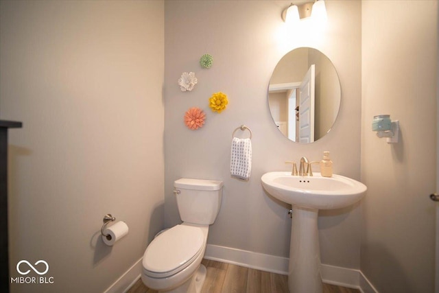 bathroom with baseboards, toilet, and wood finished floors