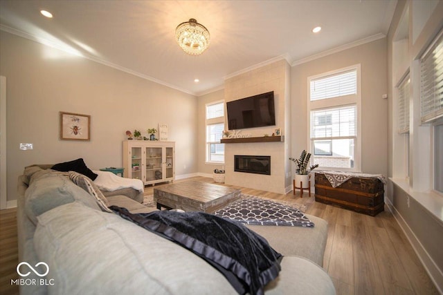 living area featuring baseboards, plenty of natural light, a tiled fireplace, and wood finished floors