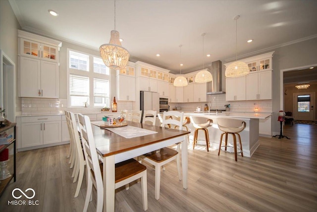 dining area featuring light wood-type flooring, crown molding, an inviting chandelier, and recessed lighting