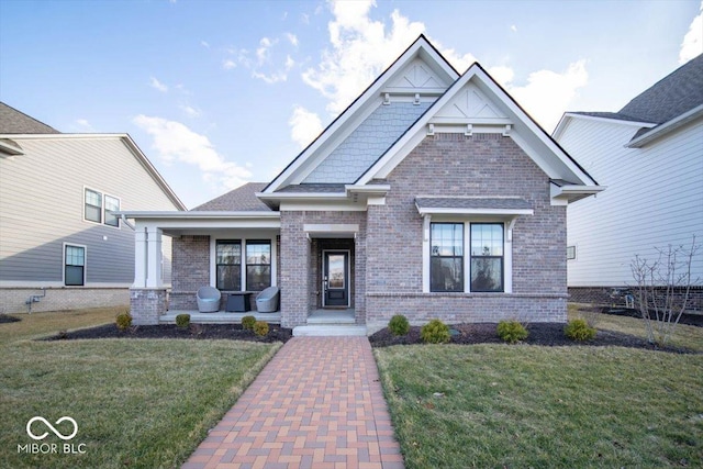 craftsman house with covered porch, brick siding, and a front yard