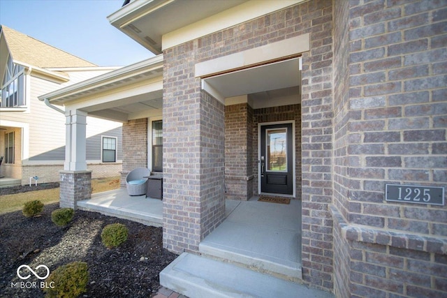 property entrance with covered porch and brick siding