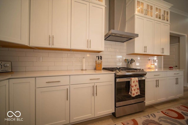 kitchen with stainless steel range with gas cooktop, light countertops, light wood finished floors, and wall chimney exhaust hood