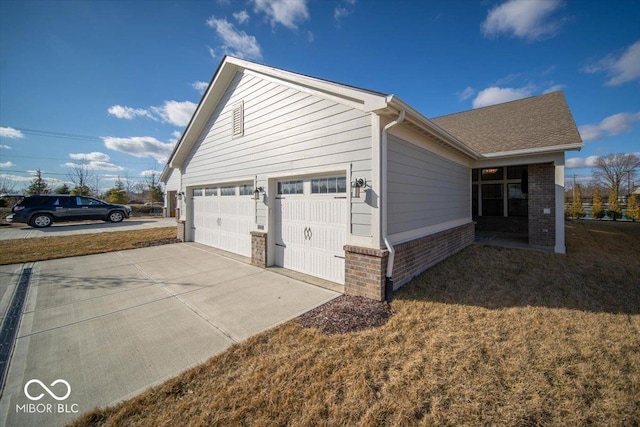 view of home's exterior featuring a garage, concrete driveway, brick siding, and a lawn