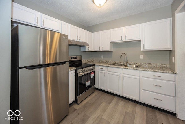 kitchen with white cabinetry, under cabinet range hood, appliances with stainless steel finishes, and a sink