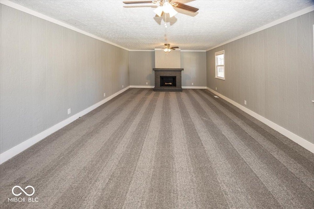 unfurnished living room featuring crown molding, carpet flooring, a fireplace, a textured ceiling, and a ceiling fan