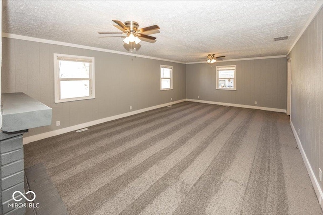 carpeted spare room featuring a ceiling fan, a textured ceiling, visible vents, and crown molding