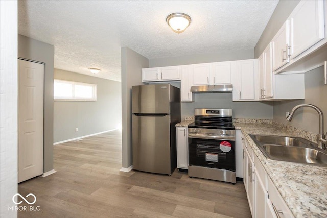 kitchen featuring light wood-style flooring, under cabinet range hood, a sink, white cabinetry, and stainless steel appliances