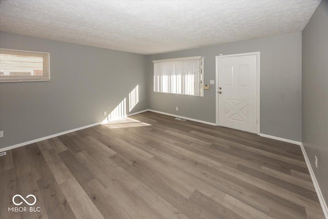 unfurnished room featuring visible vents, wood finished floors, baseboards, and a textured ceiling