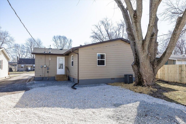 rear view of property featuring crawl space, entry steps, central AC, and fence