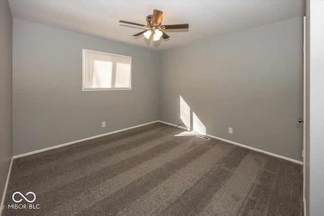 spare room with visible vents, baseboards, dark carpet, and ceiling fan