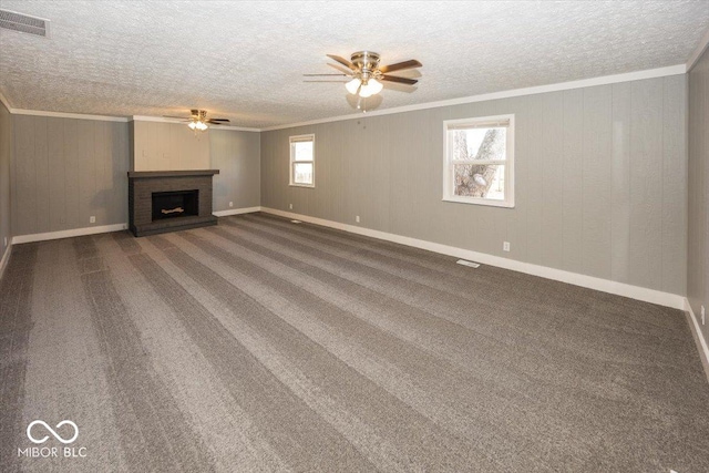 unfurnished living room featuring a ceiling fan, visible vents, a fireplace, ornamental molding, and carpet flooring