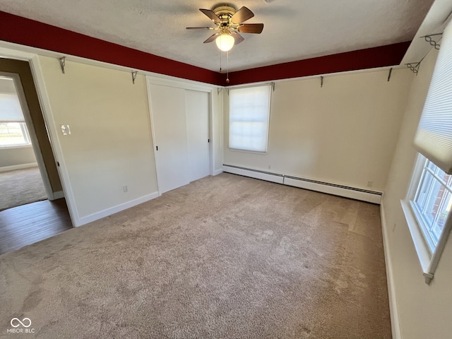 unfurnished bedroom with a ceiling fan, a baseboard radiator, light colored carpet, and baseboards