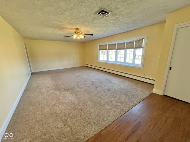 spare room with baseboards, visible vents, a ceiling fan, baseboard heating, and a textured ceiling