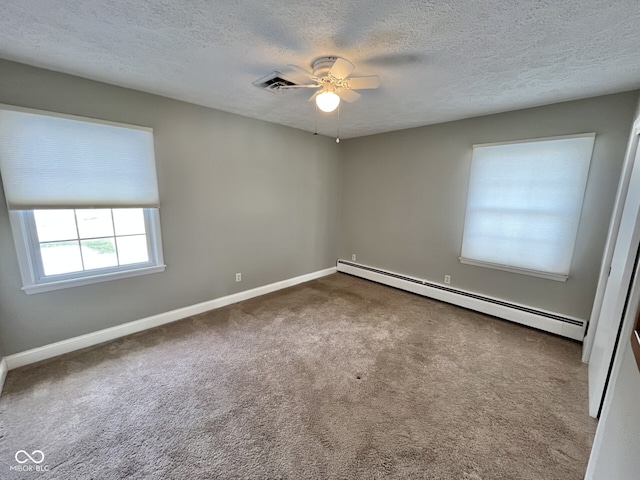 spare room featuring a baseboard heating unit, visible vents, carpet floors, and baseboards