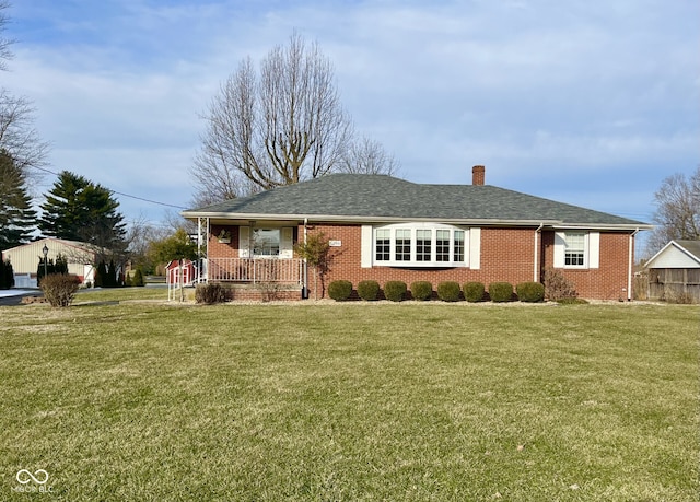 ranch-style home with brick siding, a chimney, a porch, a shingled roof, and a front lawn