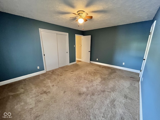 unfurnished bedroom featuring carpet, a closet, a ceiling fan, a textured ceiling, and baseboards