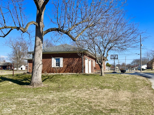 view of side of property with a yard, brick siding, and an attached garage