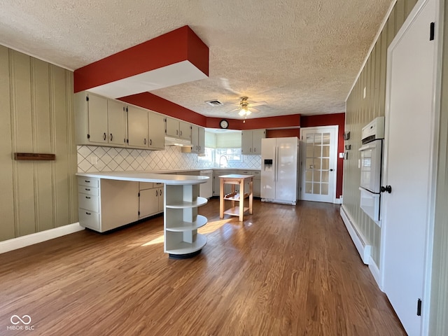 kitchen featuring light countertops, visible vents, decorative backsplash, wood finished floors, and white appliances