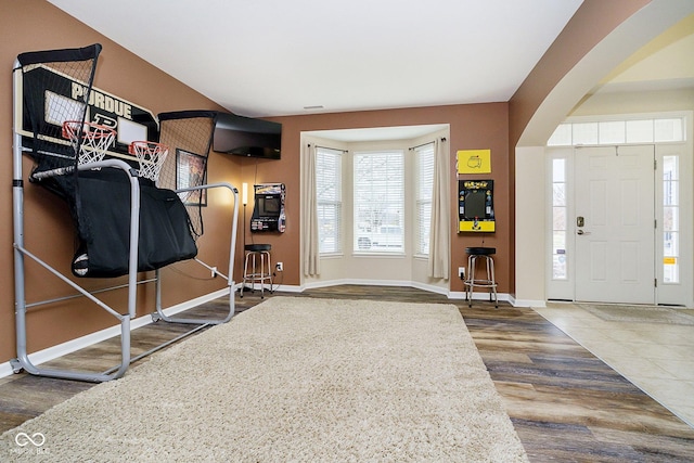 foyer with arched walkways, baseboards, and wood finished floors