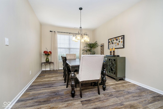 dining space with baseboards, wood finished floors, and a notable chandelier