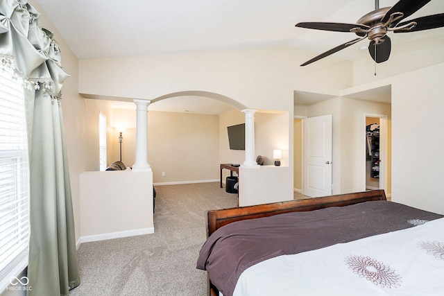 carpeted bedroom with arched walkways, ornate columns, vaulted ceiling, ceiling fan, and baseboards