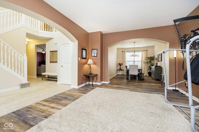 entryway with stairs, arched walkways, and wood finished floors