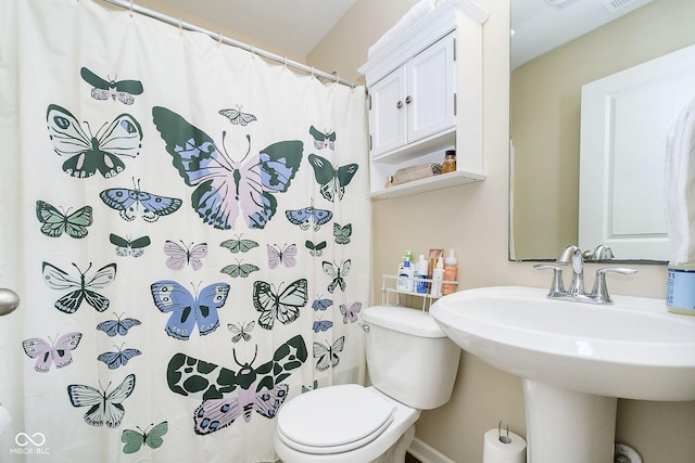 full bath with curtained shower, a sink, and toilet