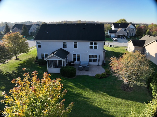 rear view of property featuring a yard, a patio area, and a sunroom